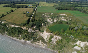 An erosive crater first seen in 2013 is encroaching on former farmland. Freeze–thaw cycles, groundwater seepage, and stronger wave action are accelerating bluff erosion, causing the land to steadily incave. Port Burwell, Ontario. Great Lakes Water in Action. Katie Franken.
