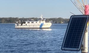 Grand Valley State University's research vessel W. G. Jackson is surveying Muskegon Lake (in the background) even as a solar-powered observatory at the lakeside pier (foreground) monitors changes in water quality. Research, Education and Science. Bopi Biddanda.