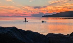 A paddle boarder and kayaker at sunset. Sault Ste Marie, Ontario. Recreation. Victoria Redegeld